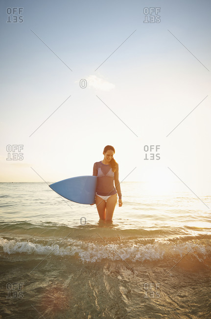 Pacific Islander woman holding surfboard in waves