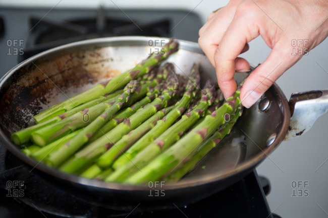 Steaming green asparagus in skillet