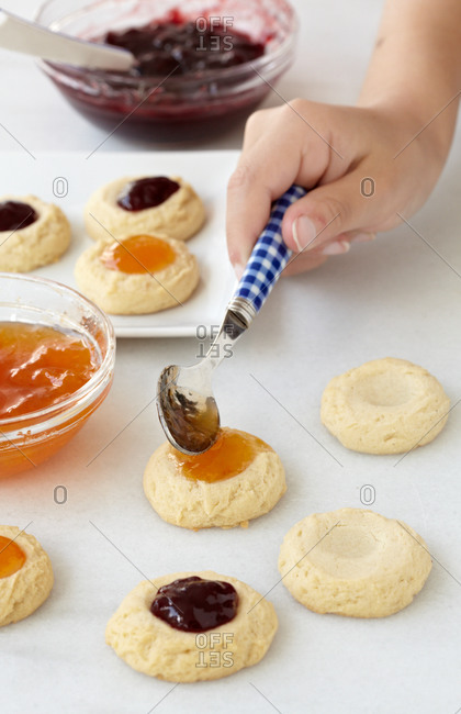 Preparing thumbprint cookies with various jam types at home
