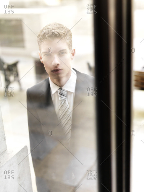 A young businessman arriving to a building, seen through window