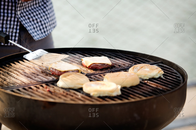 Close up of hamburger rolls and patty on grill
