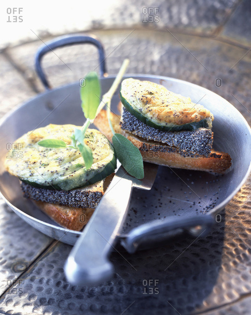 Grilled cucumber with goat\'s cheese and poppy seeds on cast iron pan