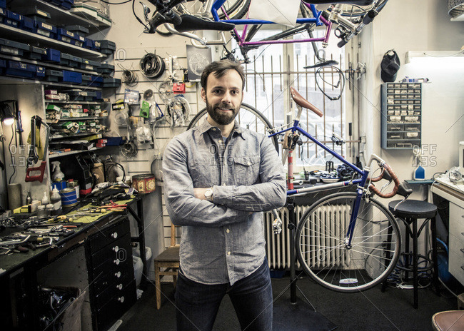 Portrait of  male owner standing arms crossed at bicycle repair shop