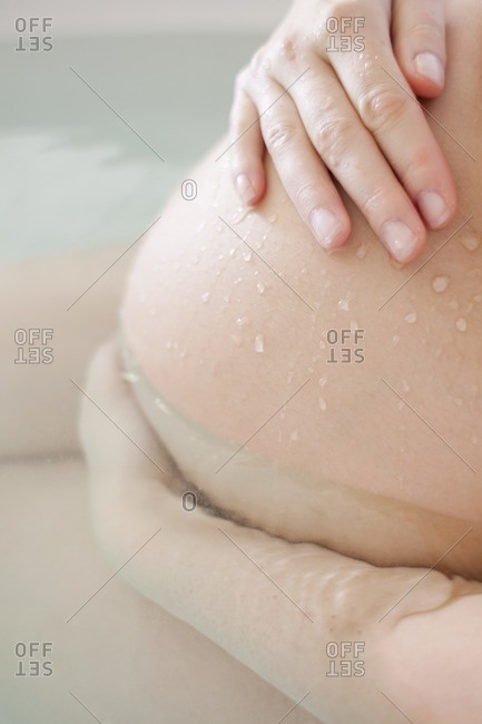 Pregnant woman sitting in a birthing pool, water birth.
