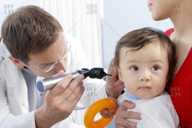 Ear examination. Otoscope being used by a general practice doctor to examine a one-year-old boy\'s ear.