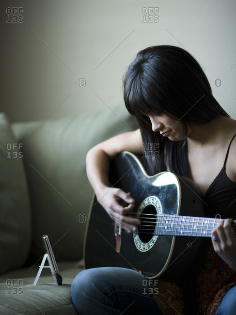 Woman tuning guitar with metronome