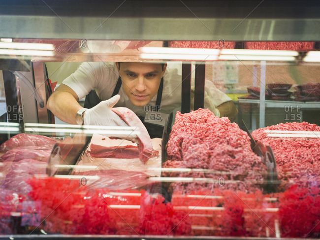 Hispanic butcher at meat counter of grocery store