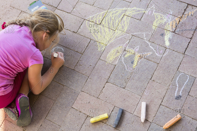 Caucasian girl drawing with chalk on brick