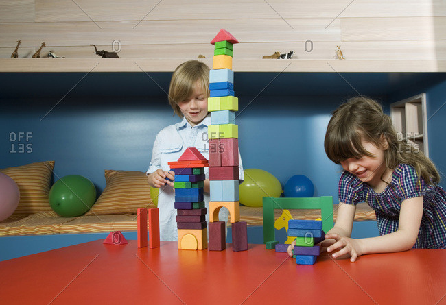 Boy (8-9) and girl (6-7) playing building bricks, portrait