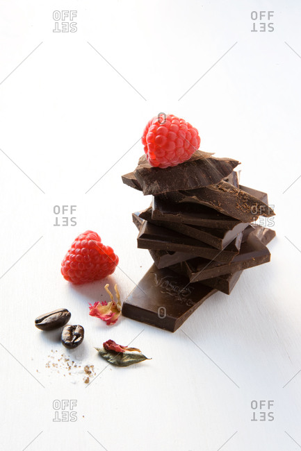Stack of dark chocolate with coffee beans, raspberries and dried flower