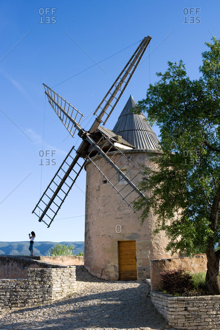 Woman taking photograph next to old windmill