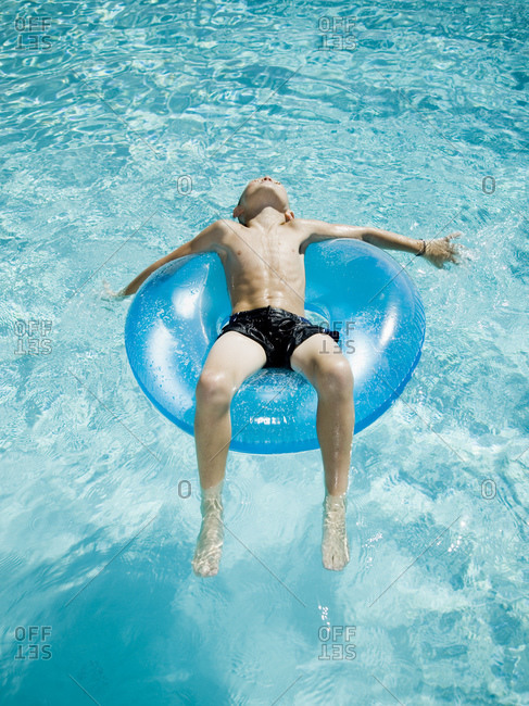 Young boy floating on life ring in swimming pool
