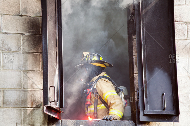 Fireman standing by the window of a burning building