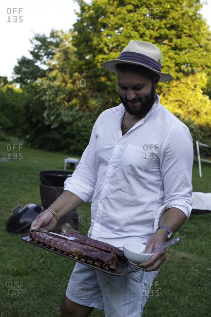 Man in hat holding barbecue ribs during garden party