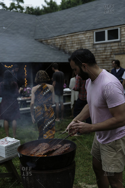 Man preparing barbecue ribs on garden party