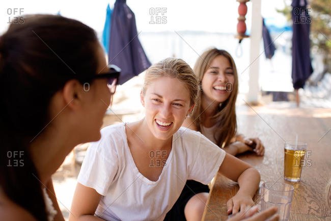 Three young women laughing at a beach bar