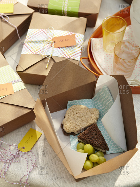 Still-life of handmade paper lunch boxes with ice cream shape sandwich and grapes.