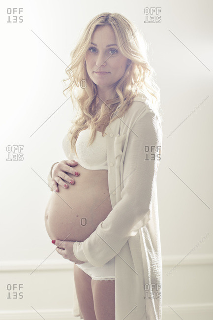 Portrait of pregnant woman holding abdomen at home