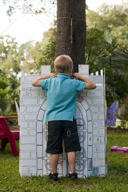 Rear view of little boy standing next to paper castle