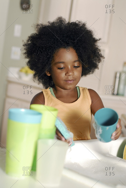 Young girl washing dishes at home