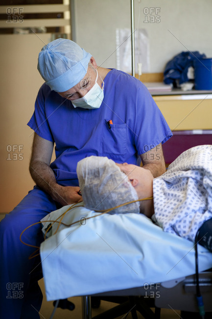Anesthesiologist communicating with patient to ensure patient maintains hypnotic state during cesarean section