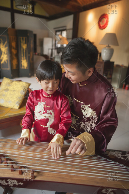 Chinese father and son in traditional clothes playing harp