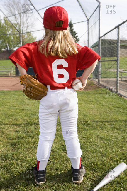 Girl in baseball uniform standing on field