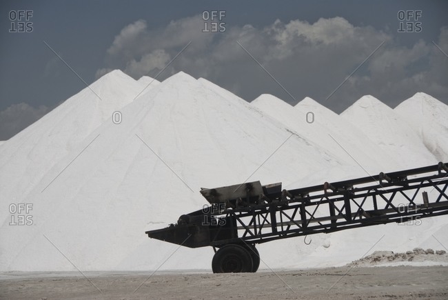 Close-up of conveyor belt with salt heaps on salt field