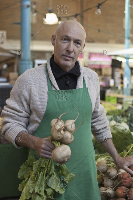Greengrocer holding a bunch of white beets