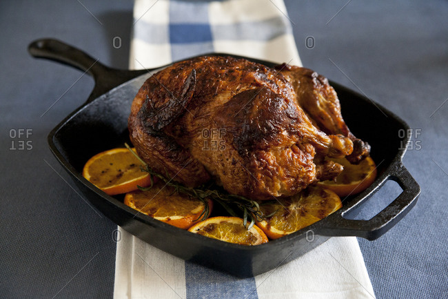 Roasted whole chicken on herbs and orange slices