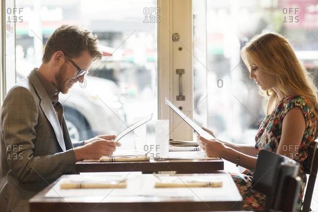 Side-view of couple looking at menu in restaurant