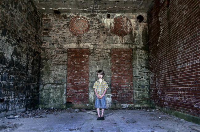 A little boy stands in a vacant brick room
