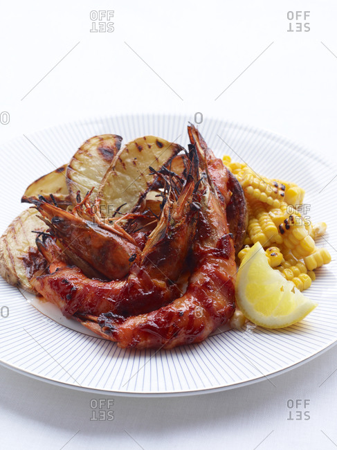 Barbecued prawns, potato wedges and corn with lemon wedge