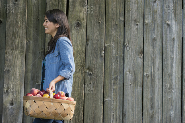 A woman carrying a basket of freshly picked fruit
