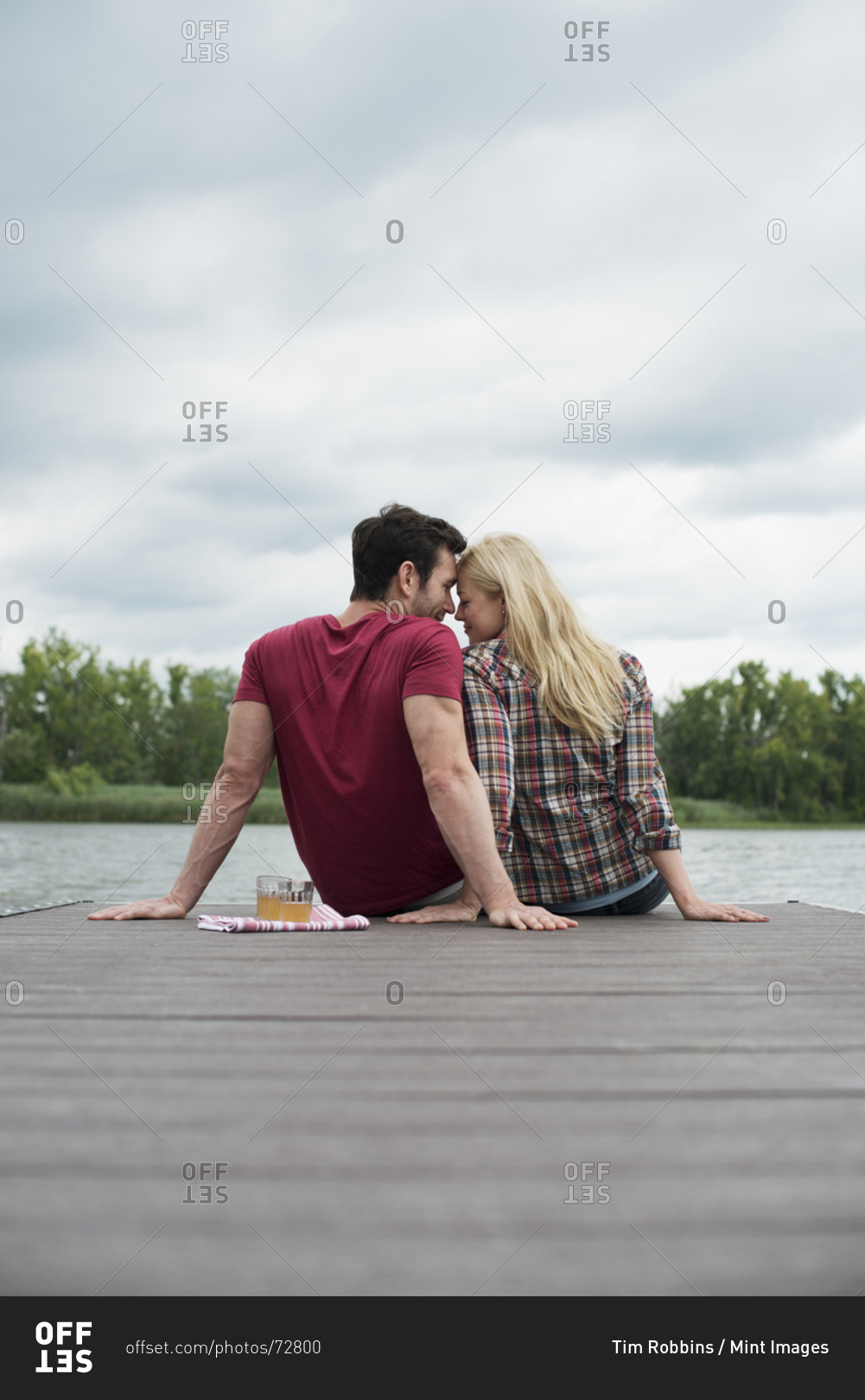 A Man And Woman Seated On A Dock By A Lake Stock Photo OFFSET