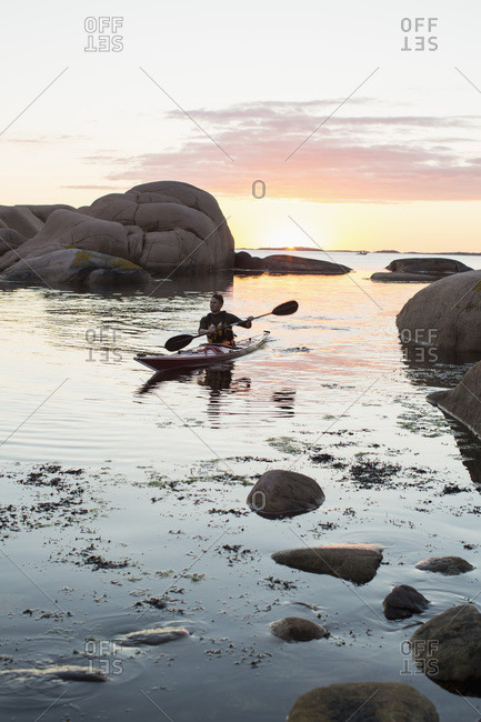 Mid adult man kayaking at dusk