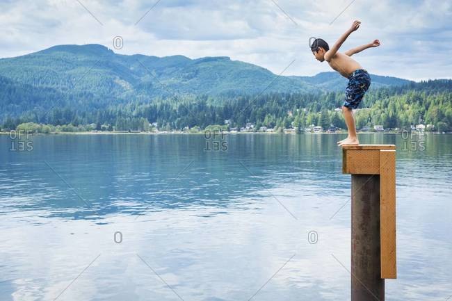 Korean boy jumping off platform into lake