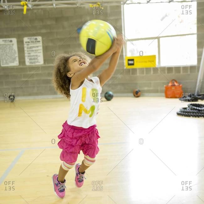 Mixed race girl playing with volleyball on court