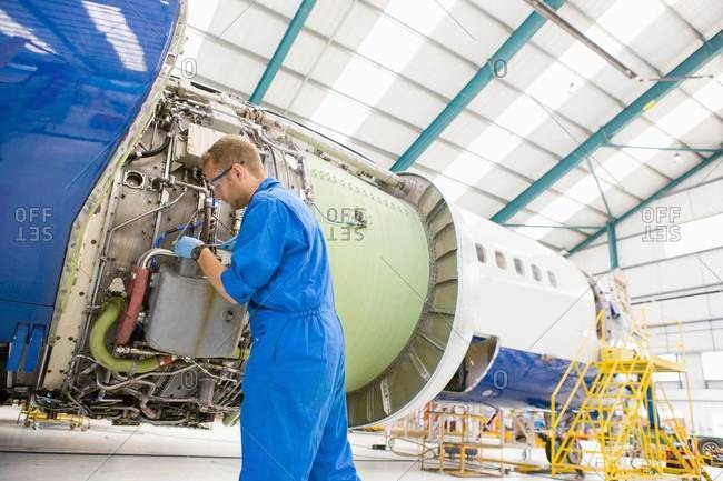 Engineer assembling engine on passenger jet in hangar