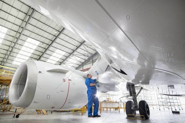 Engineer inspecting engine of passenger jet in hangar