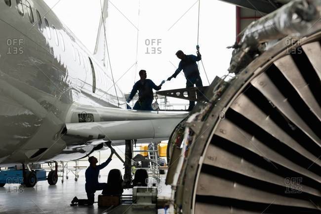 Engineers assembling passenger jet in hangar