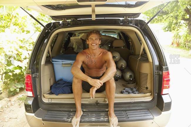 Caucasian man sitting in trunk of car