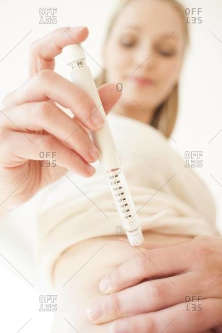 Woman injecting insulin into herself with an insulin pen