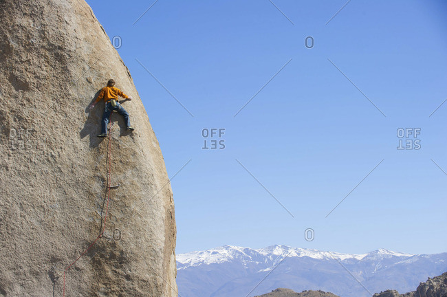 A man straddles the edge of a cliff in Bishop, California