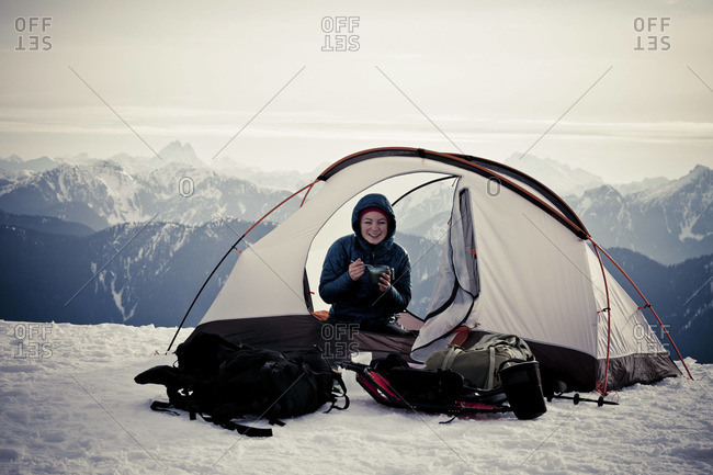 A woman enjoys a meal in a tent during winter