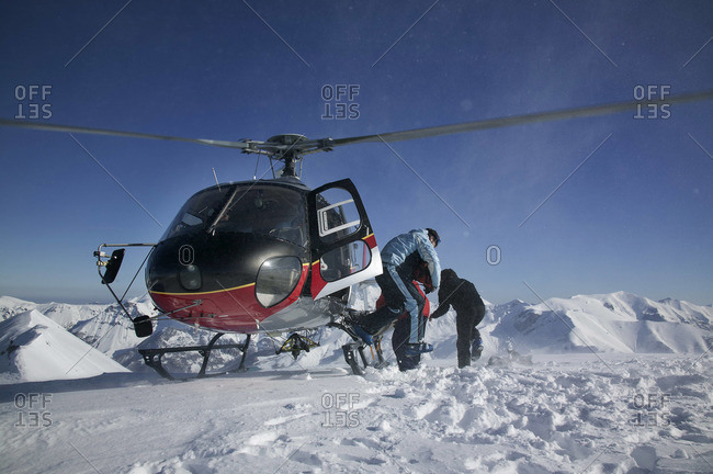 A helicopter lands with 4 off-piste skier at the top of a mountain, Limone in Italy