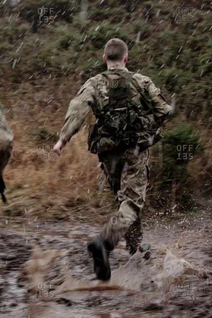 Soldier running through muddy puddles