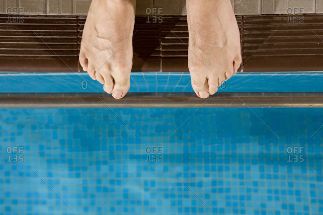 Feet hanging over the edge of swimming pool