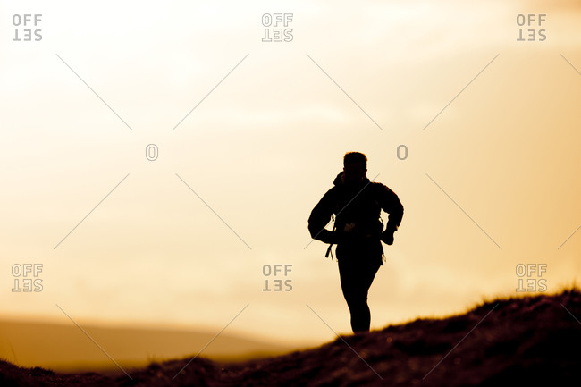 Solo outdoor runner silhouette against sunset sky