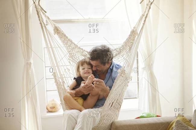Father tickling his daughter in the hammock chair